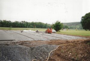 L’équipe ADN-SOL en train d’amener et de répartir le béton poreux sur un chantier, étape cruciale dans la construction d’un court de tennis durable et drainant.