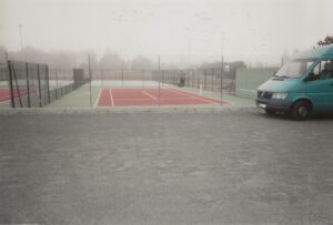 Un court de tennis en béton poreux finalisé par ADN-SOL, avec une peinture fraîche et des lignes de jeu tracées, prêt à accueillir les joueurs.