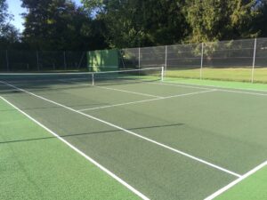 Un court de tennis en béton poreux rénové avec expertise par ADN-SOL, offrant une surface de jeu uniforme et performante.