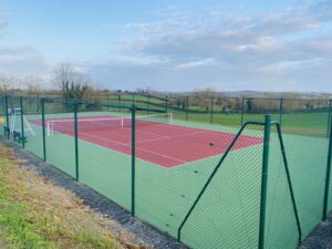 Un court de tennis en béton poreux finalisé par ADN-SOL, avec une peinture impeccable, des lignes de jeu tracées avec précision et un système d’éclairage moderne installé.