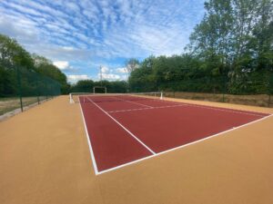 Un court en béton poreux polyvalent conçu par ADN-SOL, utilisé à la fois comme terrain de tennis et terrain multisport pour diverses activités.