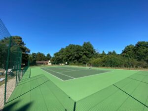 Un court de tennis en béton poreux finalisé par ADN-SOL, réceptionné par des représentants de la mairie, satisfaits du travail accompli.